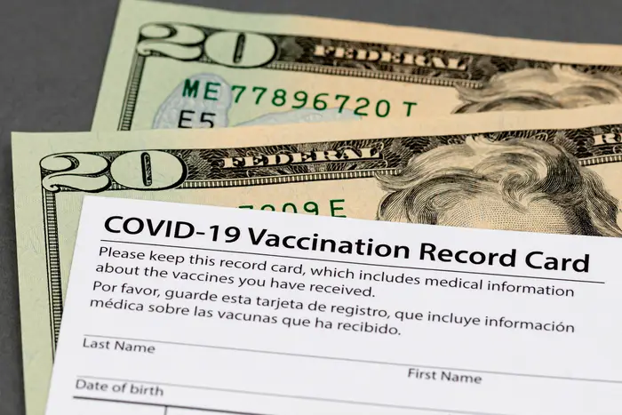 COVID-19 vaccination card and cash money